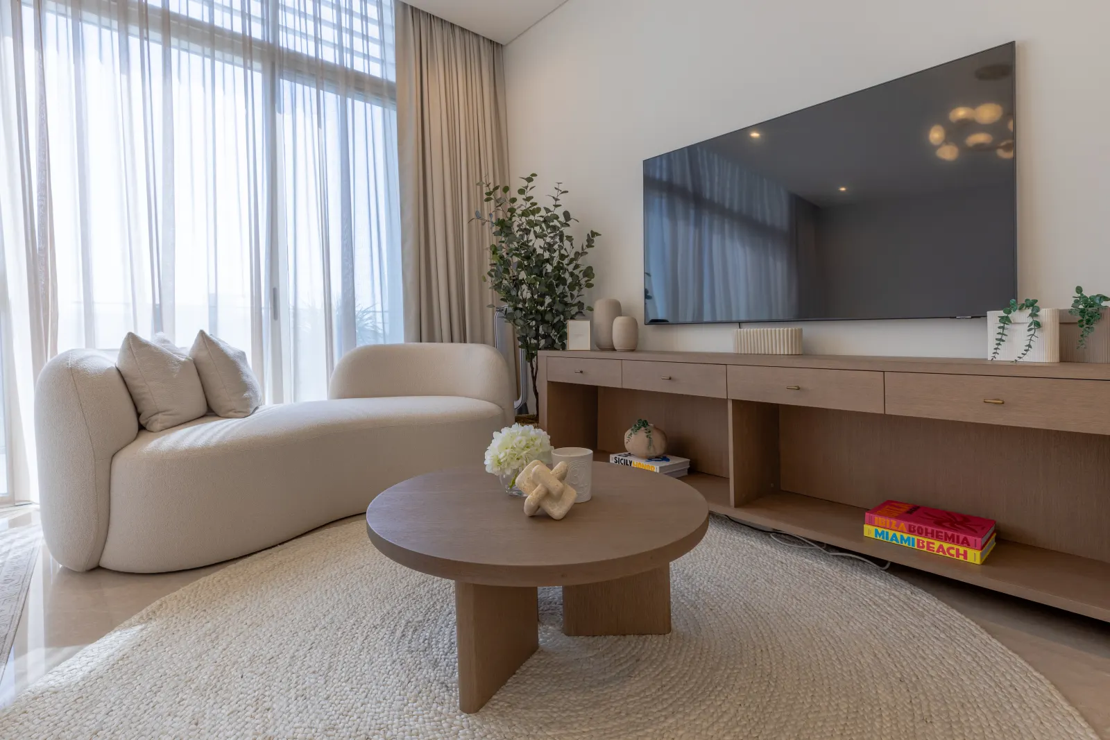 Alwan Fit-out renovation, Dubai Hills villa secondary living. Boucle daybed, sculpted oak coffee table, curtain wall.