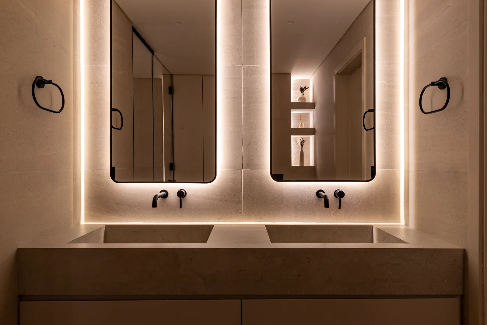Alwan Fit-out renovation, Turk Villa master bathroom. Backlit twin mirrors, stone vanity, warm indirect light.